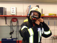 Die volle Montur: Feuerwehr-Schutzkleidung inklusive Gurt, Helm und Handschuhe, dazu 16 Kilogramm Pressluftatmer auf dem Rücken.